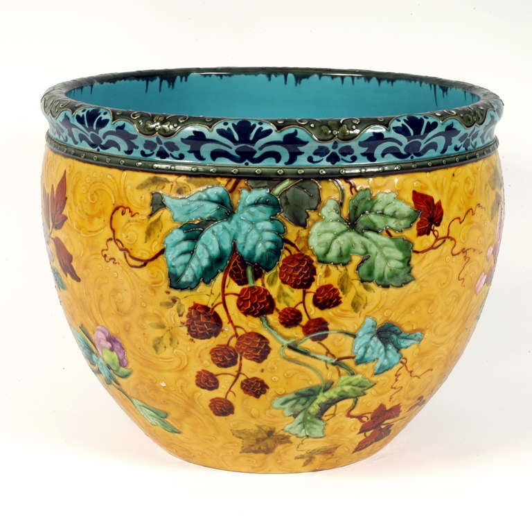 Earthenware with hand-painted decoration of flowers, leaves and butterflies against a golden yellow field. The top banded with a blue serall border. Impressed “MLA Paris” mark, oval “Exposition Universally 1889 Medaille D’Or” mark, 