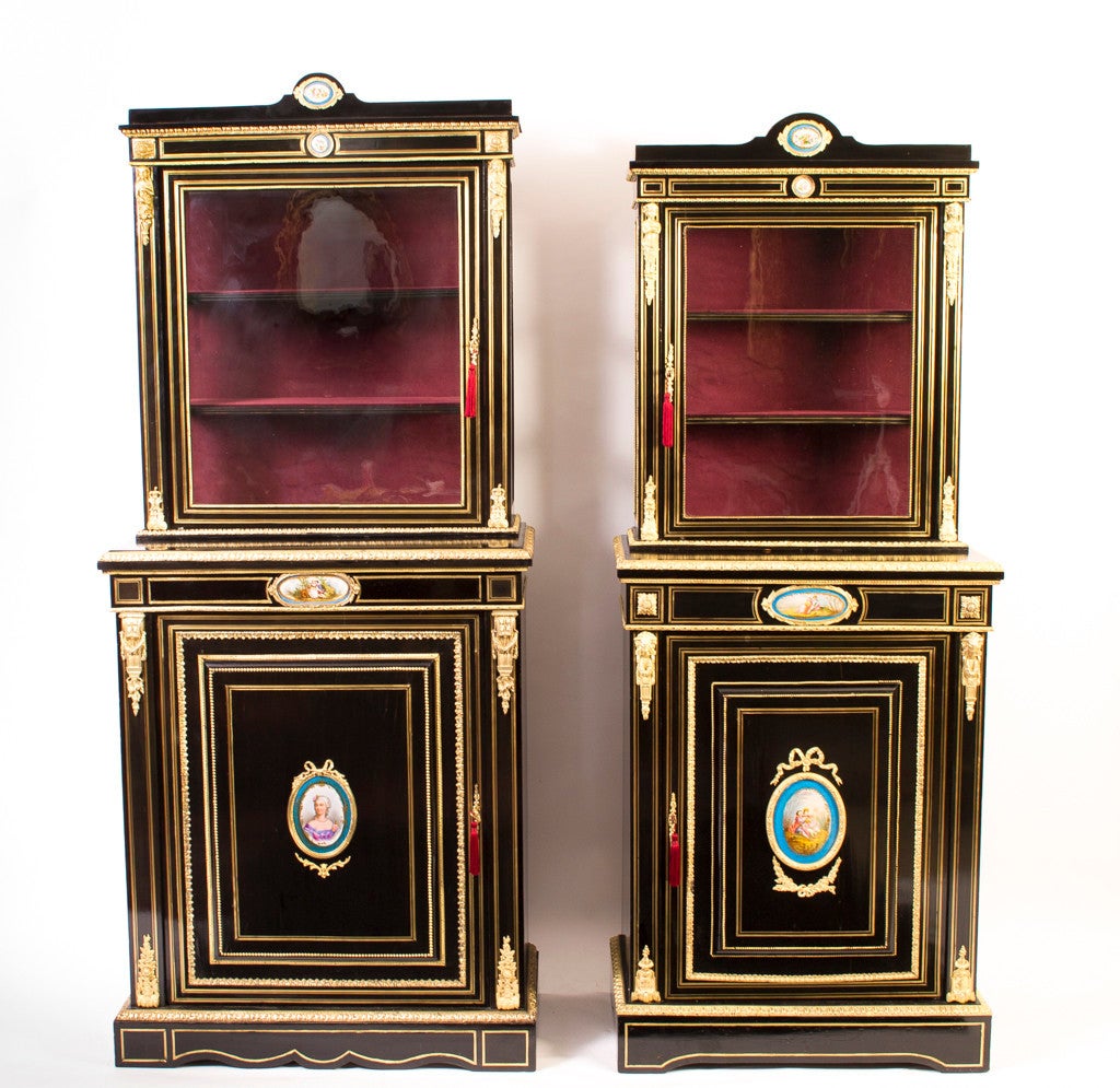 This is a gorgeous near pair of antique French porcelain and gilded ormolu mounted, brass inlaid, ebonised display cabinets c.1860 in date. 

The smaller hand painted Sevres porcelain plaques have floral motifs, the large oval plaques depict a
