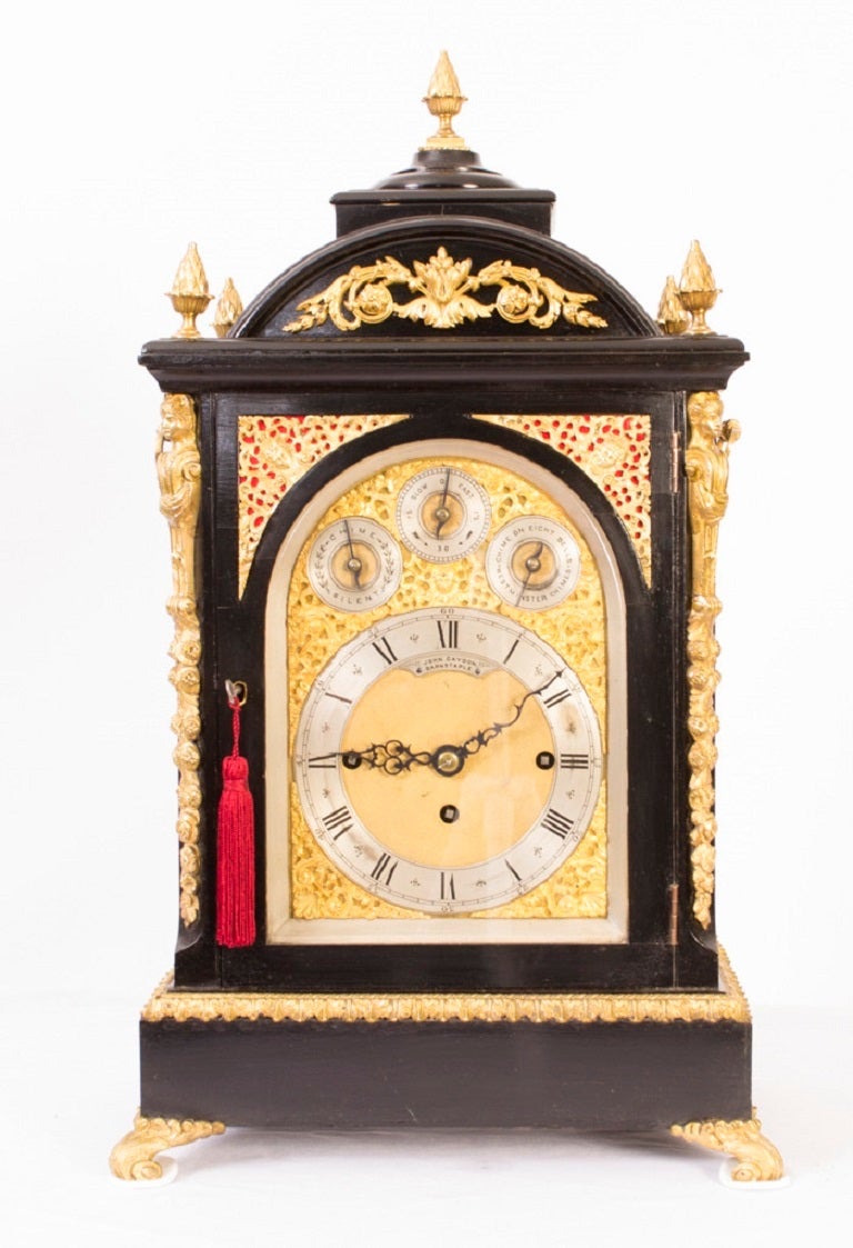 This is an antique ormolu mounted and ebonised chiming mantel clock, circa 1860 in date . The dial is signed John Gaydon, Barnstaple. 

The clock has a rectangular case with pineapple urn finials, the arched pediment with a floral mount and turned