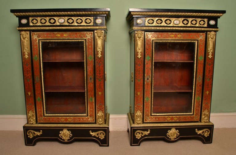 This is a stunning pair of antique Victorian ebonised walnut, gilt ormolu and Sevres mounted, red and green tortoiseshell cut brass boulle marquetry, pier cabinets, from the third quarter of the 19th Century, and Circa 1860 in date. 

The cabinets
