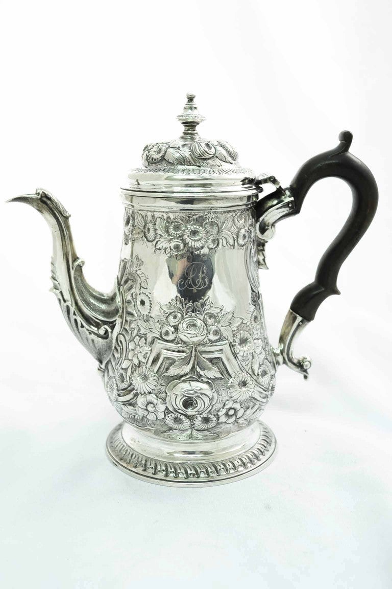 This is a beautiful English antique George II silver coffee pot with wonderful embossed decoration.

It has hallmarks for London 1753, and the makers mark of Robert Albin Cox.

There is no mistaking its unique quality and design, which is sure