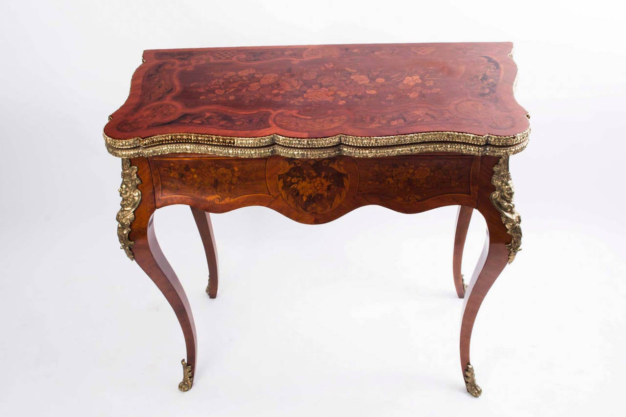 This is a beautiful antique French walnut and marquetry card table with fabulous ormolu mounts, circa 1910. 

It is beautifully inlaid with floral marquetry, has a plethora of exquisite ormolu mounts and stands on elegant cabriole legs terminating