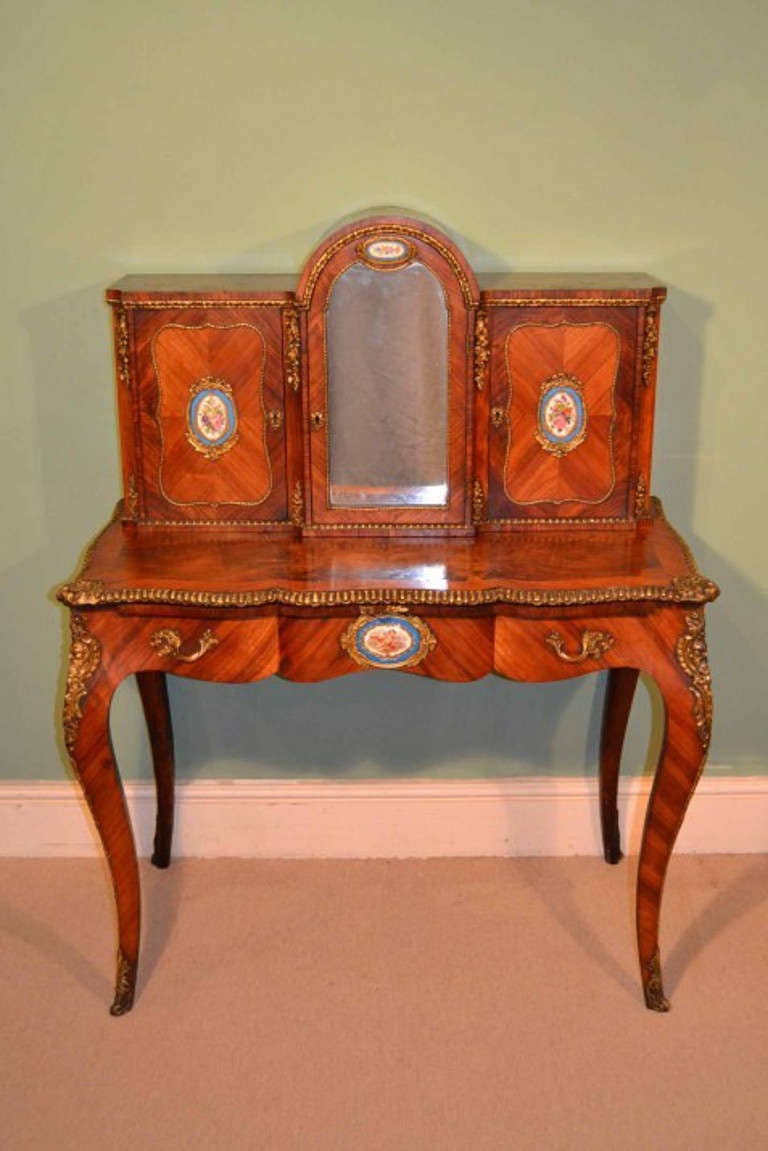 This is a gorgeous Victorian burr walnut and tulipwood, Bonheur Du Jour, or Ladies writing desk, with Sevres porcelain plaques, circa 1860 in date.

The superstructure comprises a central arched mirror inset door enclosing one shelf, flanked by