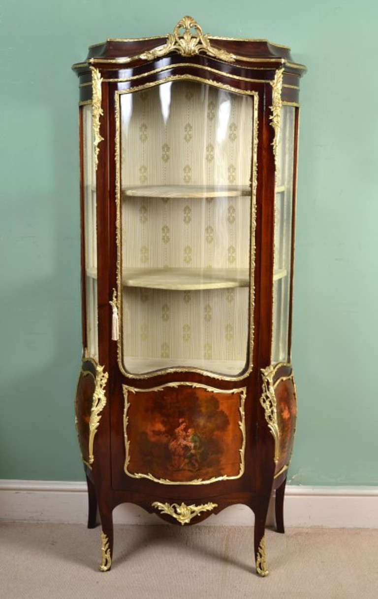This is a lovely antique French Vernis Martin mahogany serpentine vitrine in the Louis XV manner, circa 1880 in date.

This beautiful cabinet has hand painted decoration and ormolu mounts. The central panel has a beautiful painting depicting a