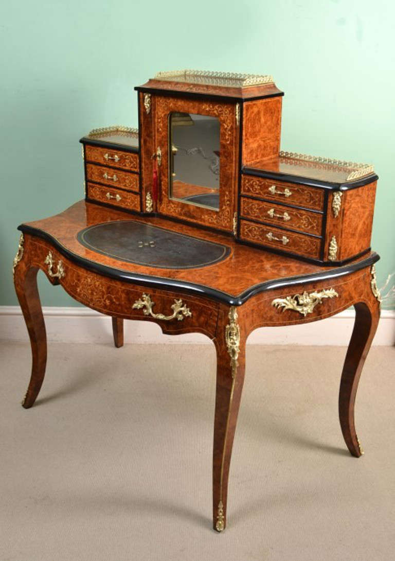 This is a gorgeous Victorian burr walnut, marquetry Bonheur Du Jour, or Ladies writing desk, circa 1860 in date.

The superstructure comprises a large central bay with a mirror inset door and brass gallery above. The door enclosing one shelf,