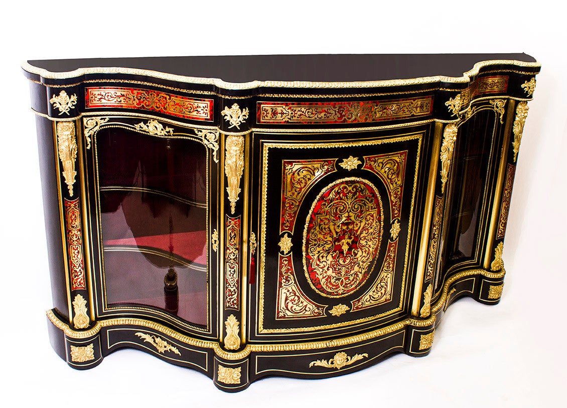 This is an important antique, Victorian, ebonised, ormolu mounted, and red Boulle marquetry serpentine credenza, circa 1870 in date.

It is beautifully inlaid in cut brass with a jester in the centre of the panel in the central door, in addition
