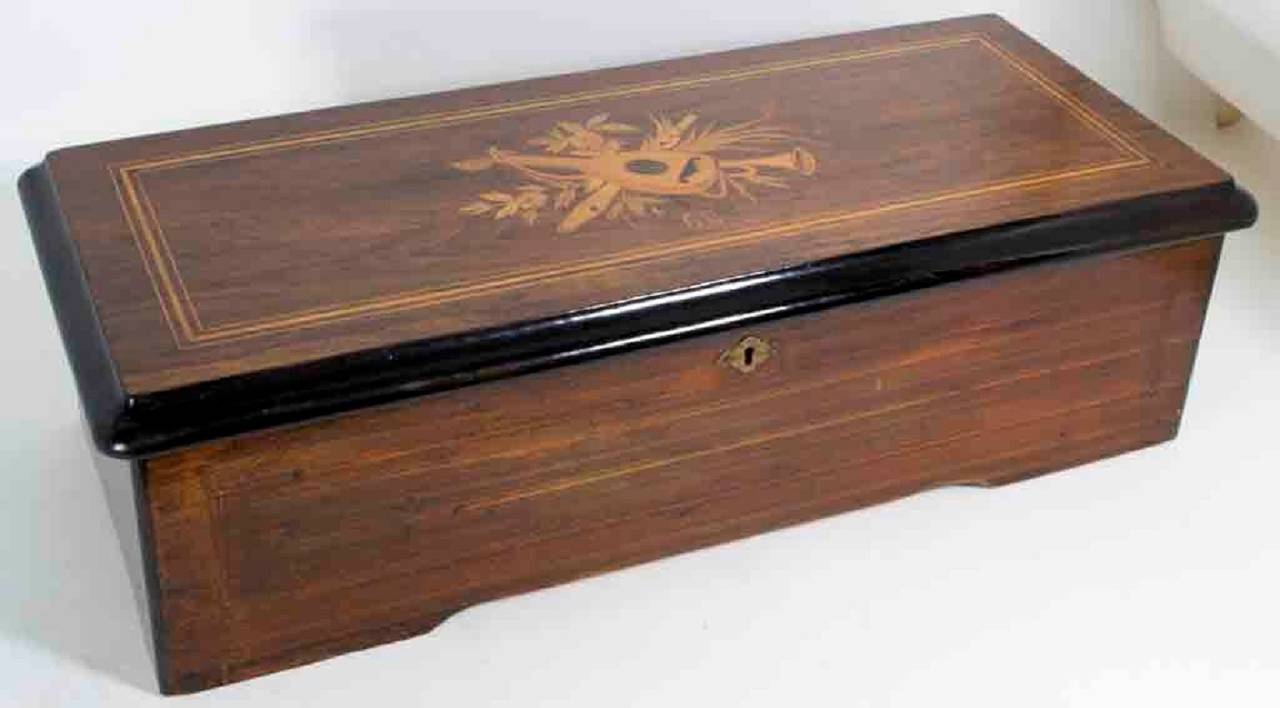 This is a lovely antique Swiss 6 airs rosewood cylinder music box, circa 1890. 
The hinged marquetry lid opens to reveal a cylinder with a comb. The tune sheet with serial number 43847 was printed by Picard-Lion Geneve. 

The beautiful rosewood