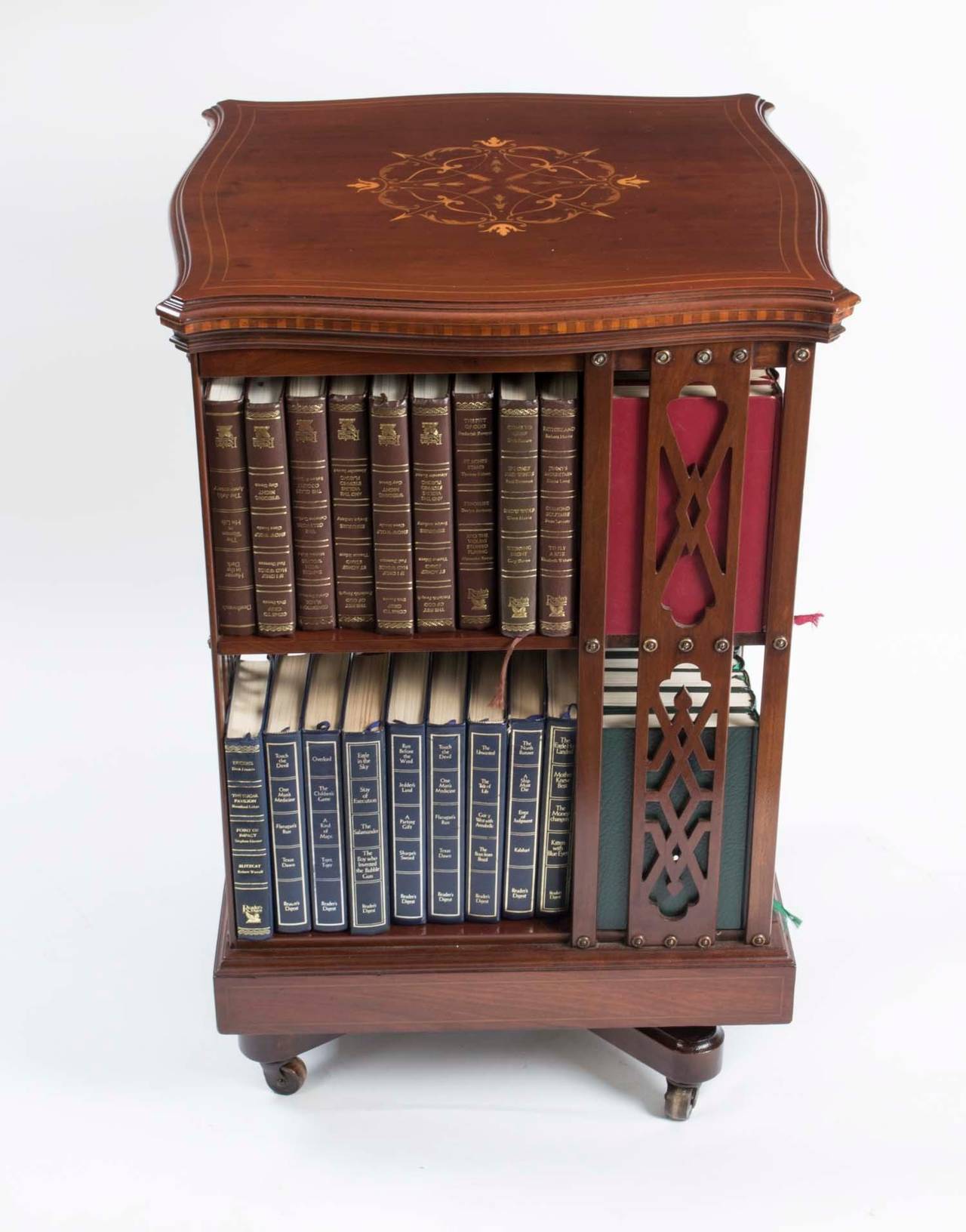 This is an English antique mahogany revolving bookcase circa 1900 in date, attributed to the renowned manufacturer and retailer Maple & Co. 

The bookcase has inlaid boxwood lines to the top and bottom. The top has an elaborate fruitwood inlay to