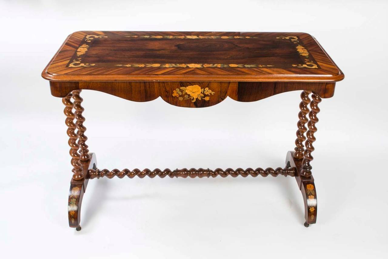 This is a rare antique Victorian stretcher or sofa table, circa 1860 in date. 

It is exquisitely crafted from rosewood and walnut with a beautiful floral marquetry inlaid top as well as a solid walnut hand- carved barley twist base also with