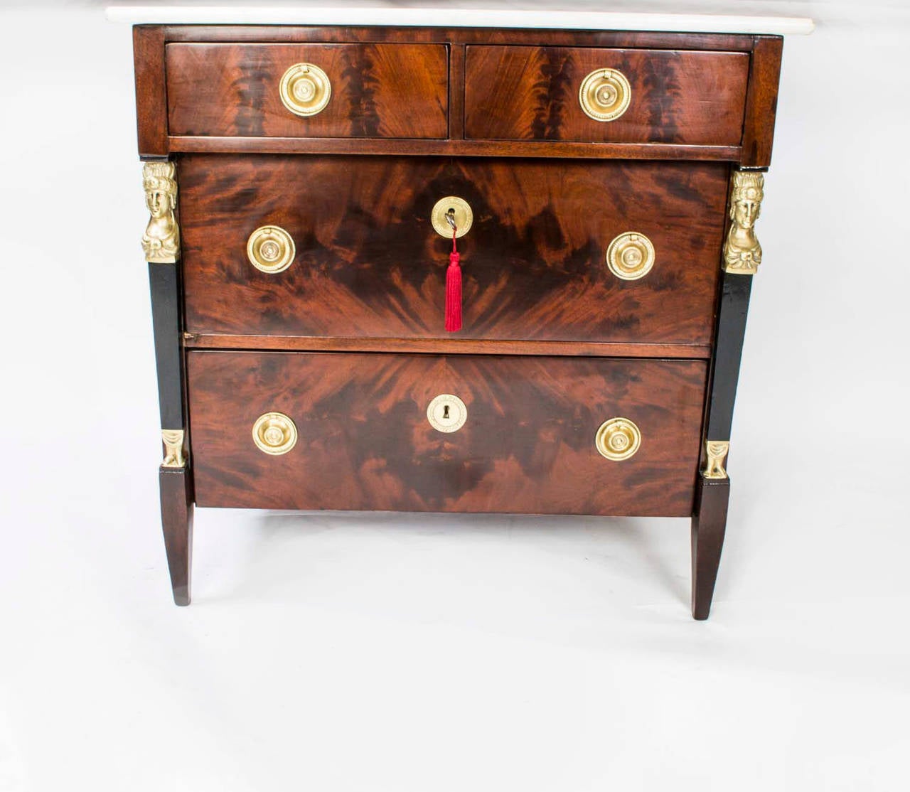 This is a stunning small antique French Empire chest which was crafted from the most beautiful flame mahogany and dates from circa 1820. 

The commode has two half width drawers above two full width drawers. It has the most wonderful ormolu