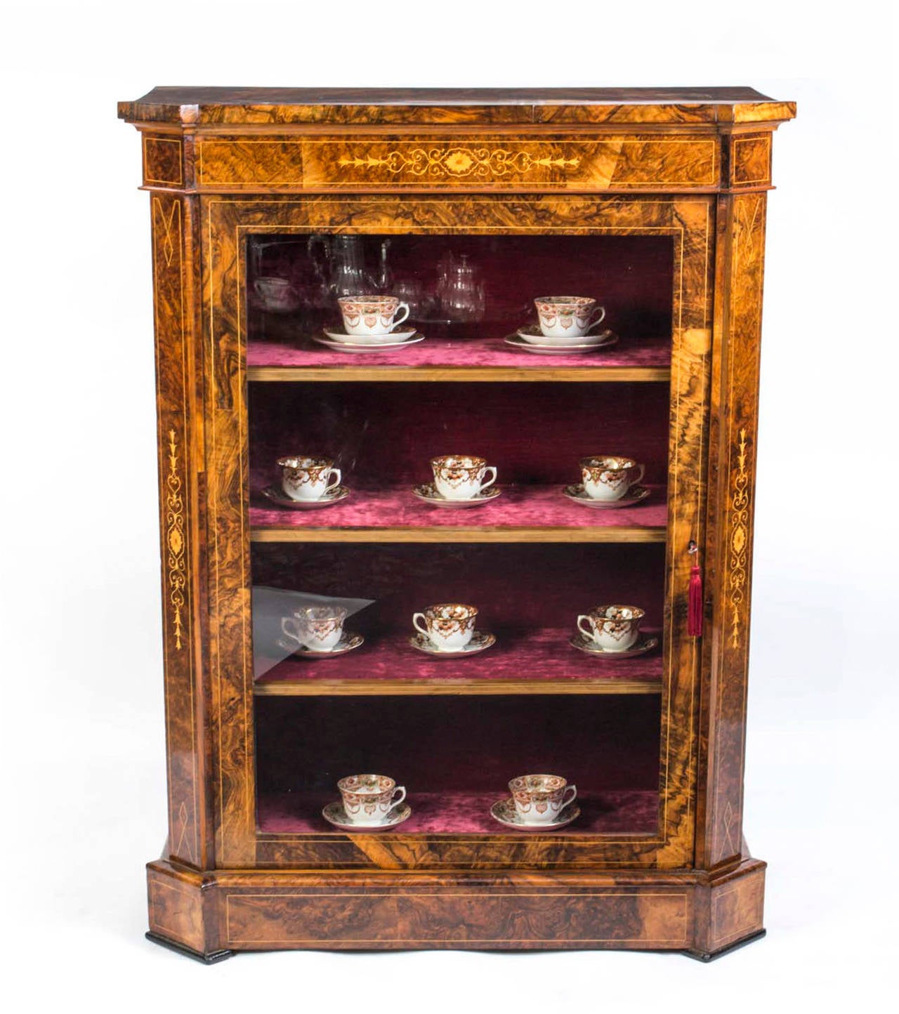 This is a lovely antique Victorian burr walnut pier cabinet, circa 1860. 

It has been accomplished in burr walnut with a glazed door enclosing interiors lined with burgundy velvet and three shelves. 

It is an unusually tall for a pier cabinet