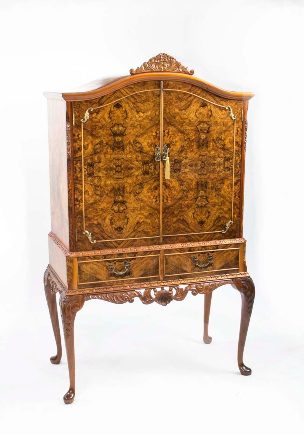 This is a fantastic vintage burr walnut cocktail cabinet with wonderful hand carved decoration dating from the mid 20th Century. 

The doors open to reveal a stunning fitted mirrored interior with a glass shelf, a useful pull out slide and a tray