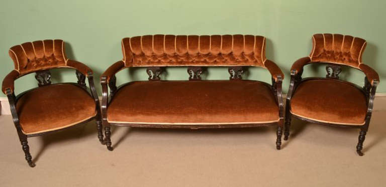 This is a fantastic English antique Victorian mahogany three piece suite, comprising a sofa and a pair of tub armchairs, circa 1890 in date. 

The mahogany frames have beautiful hand carved  decoration, deep buttoned stuff-over, terracota
