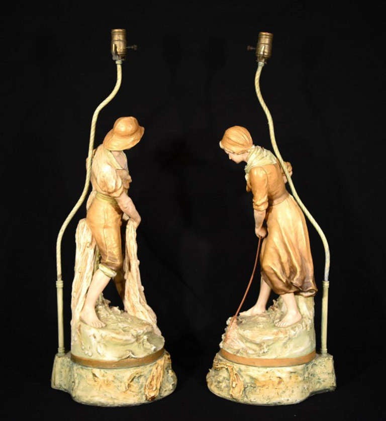 This is a fantastic pair of antique Royal Dux porcelain lamps of a fisherman and fisherwoman, with hand painted and gilded decoration, dating from Circa 1890. 

Dimensions in cm: 

Height 80 x Width 27 x Depth 27 - Male 

Height 79 x Width 26