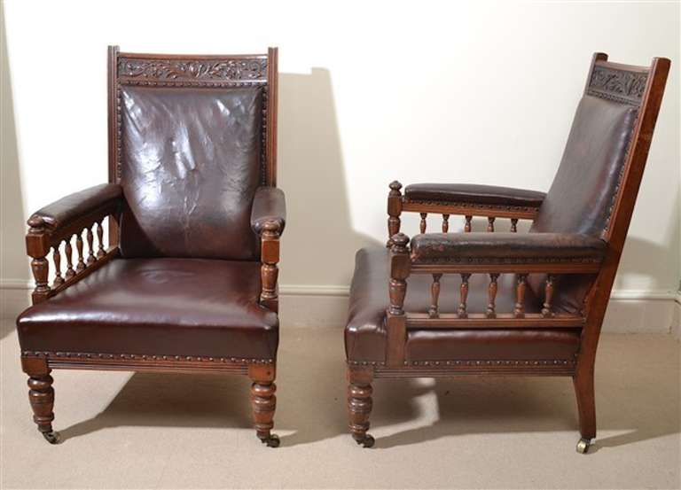 This is an absolutely magnificent pair of antique English solid walnut library armchairs, circa 1880 in date.

Each with a beautiful hand carved cresting rail, the backs, seats and arms upholstered in sumptuous leather, the arms on spindle