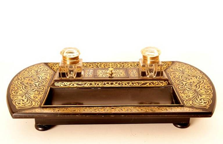 This is a lovely antique French ebonised cut brass Boulle work encrier, circa 1840 in date and made in the manner of George Bullock. The encrier comprises two glass inkwells and a lidded stamp box with a sunken well. The edges bear exquisite cut