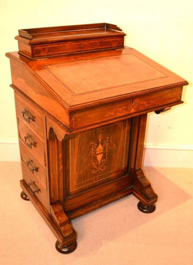 This is a beautiful Edwardian rosewood and inlaid Davenport Circa 1890 in date. 

The top has a beautiful antiqued coral leather writing surface which has gilt-tooled decoration. The inlaid urn and swags marquetry was masterfully executed by a