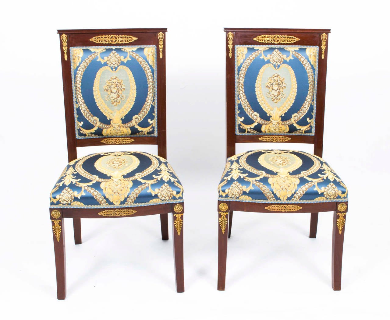 This is an elegant antique set of eight mahogany dining chairs in the fabulous Empire style, circa 1920 in date. 

The mahogany is beautiful in colour and has been embellished with striking ormolu mounts typical of the Empire period. Each chair