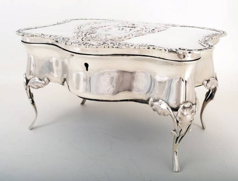 This is a stylish antique sterling silver jewelry and ring casket. 

It has hallmarks for London 1905 and the makers mark of the renowned silversmiths William Comyns. 

The top bears a beautiful embossed decoration of a romantic couple. 

The