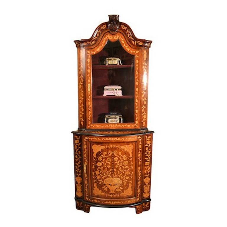 This is an antique Dutch walnut marquetry bow front corner cabinet which dates from circa 1800 and bears the brass plaque of the retailer S & H Jewell. 

The cabinet has fabulous inlaid marquetry of urns, flowers, butterflies, birds, foliage and