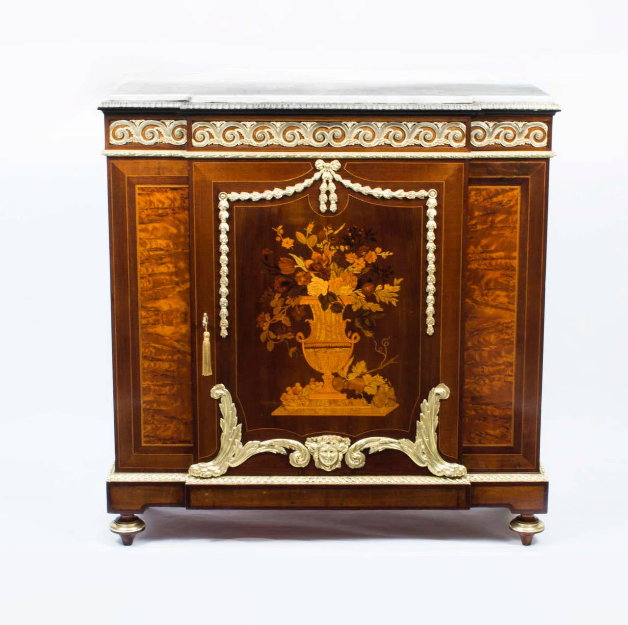 This is a beautiful 19th century French marquetry cabinet, Louis XV style, with white Carrara marble top above a frieze bearing fabulous gilded bronze ormolu mounts, the marquetry single door depicting an urn of flowers, and the cabinet standing on