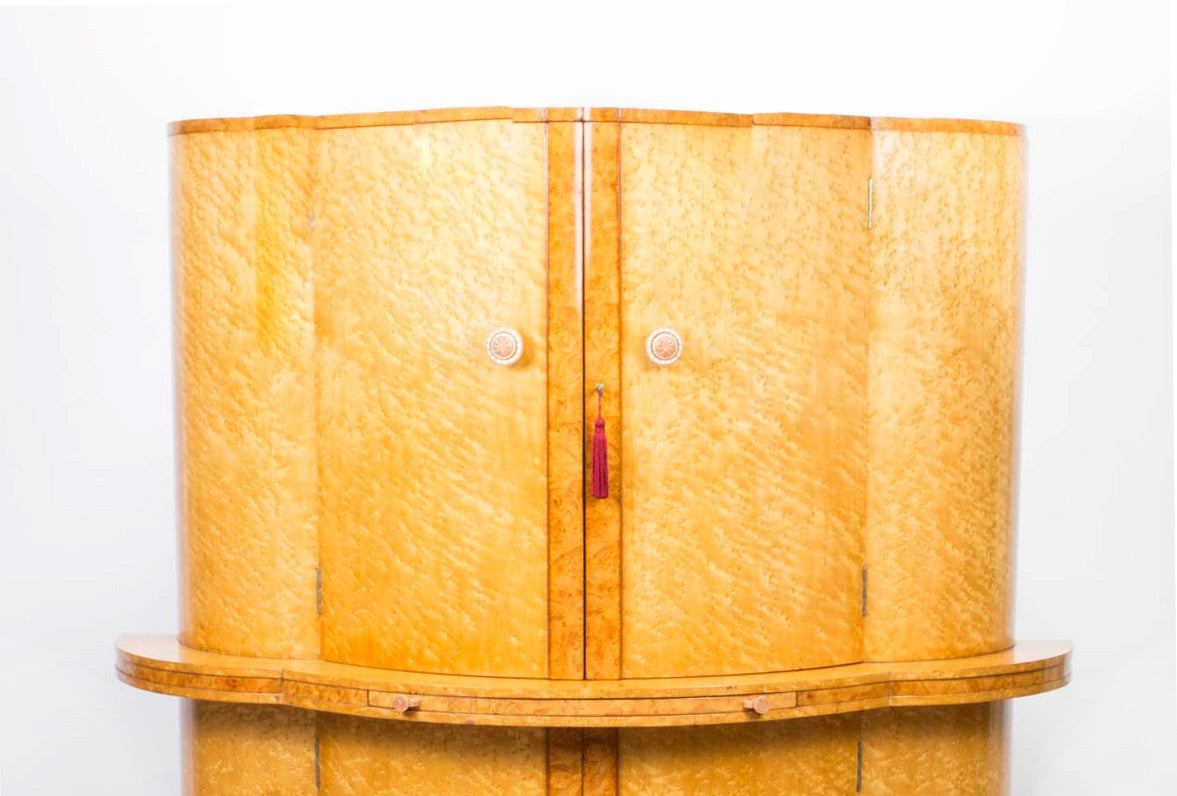 This is a spectacular antique Art Deco birdseye maple cocktail cabinet attributed to Hille, circa 1925 in date. 

It is of bow fronted form and made in beautiful birdseye maple, the upper part comprises a pair of doors enclosing a fitted maple and