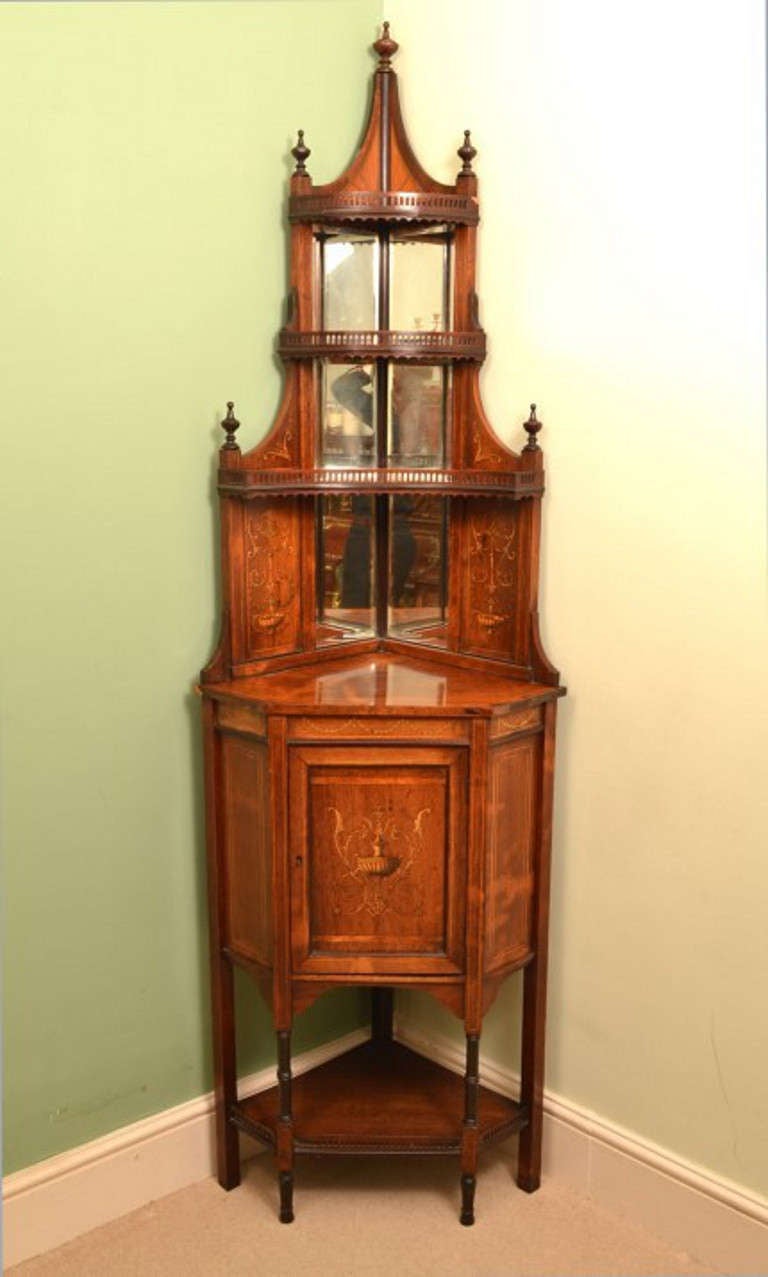 This is a beautiful antique rosewood and marquetry inlaid corner cabinet with three raised and mirrored tiers, on turned supports c.1900 in date. 

It is made from superb quality rosewood with intricate marquetry decoration that was the work of an