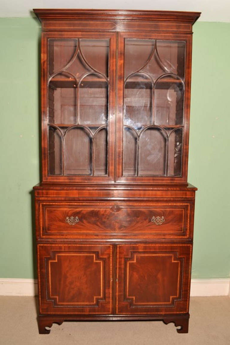 This is a beautiful antique George III flame mahogany and satinwood crossbanded secretaire bookcase, circa 1815 in date. 

The bookcase has an elegant moulded cornice, a pair of arched astragal glazed doors opening to a pair of adjustable shelves