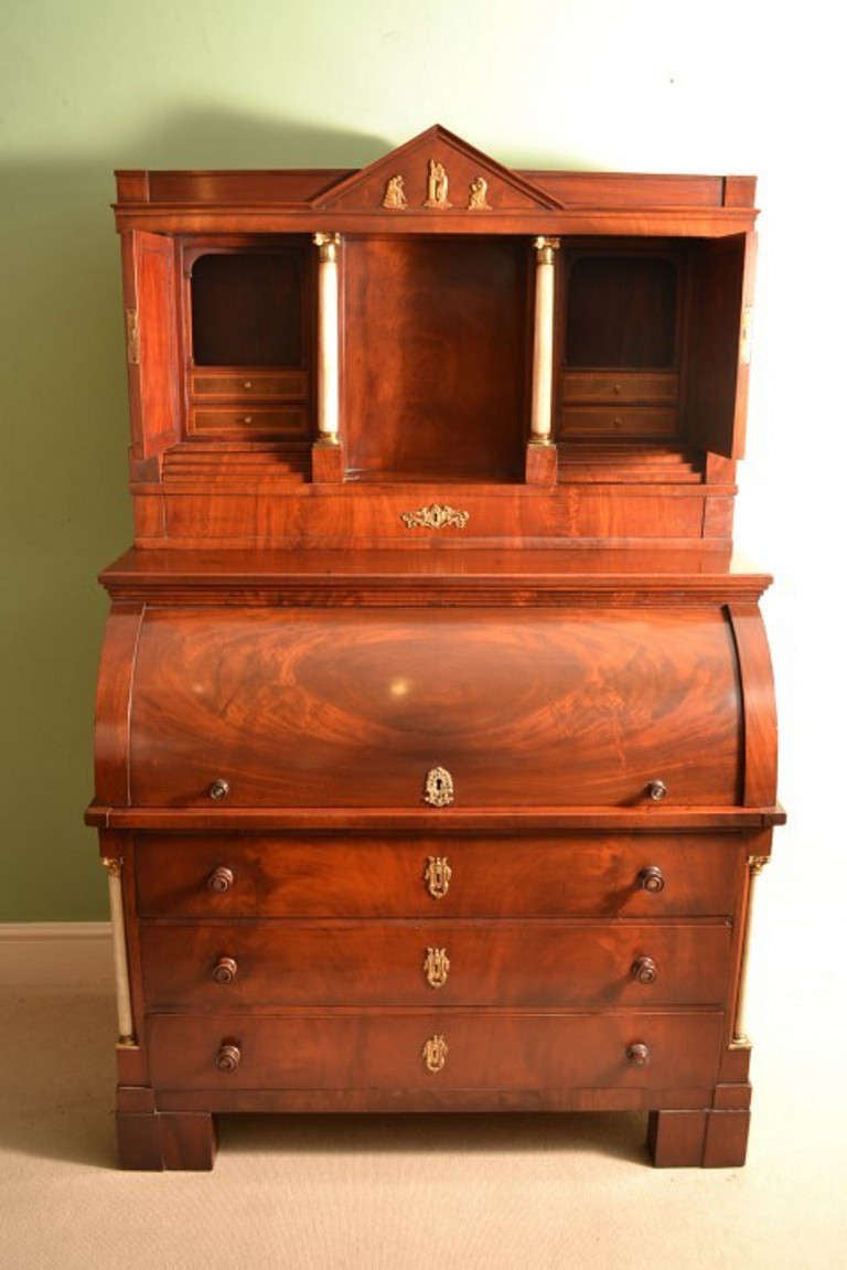This is a beautiful, antique French Louis Philippe Biedermeier flame mahogany, alabaster and ormolu, mounted cylinder desk, circa 1840 in date. 

It has an architectural upper section with a pediment decorated with classical maidens. A pair of