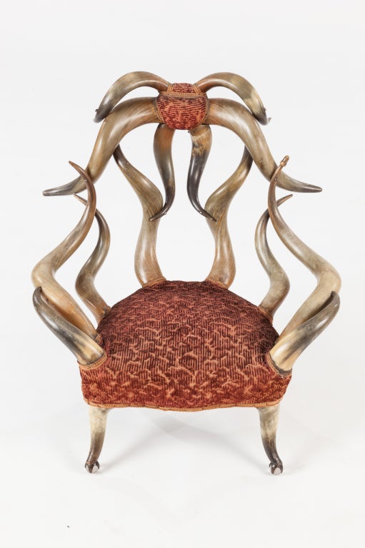 Longhorn legs and arms on victorian velvet upholstered glass ball feet chair, carved acorn on one horn is signature.