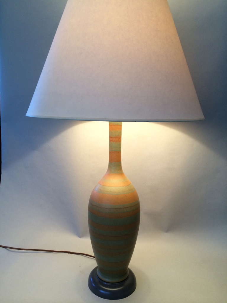 Single, bottle form table lamp, with hand applied, matte glazing in horizontal bands. Soothing to the eye, with subtle color combinations. Mounted on a painted metal base, with new brass hardware. Glidden hired excellent studio potters, to create a