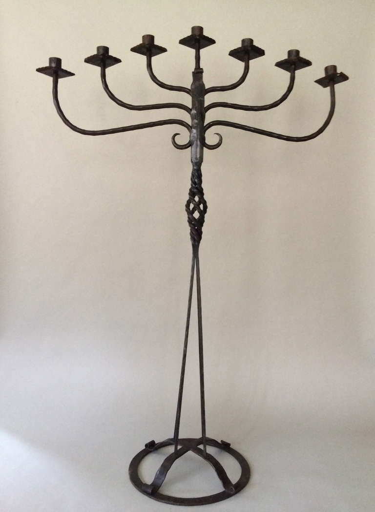 Hand-forged iron candelabra. Tall, elegant iron artistry, with subtle detailing. Circular base with tapering stems and open barley twist center. Base in stamped 