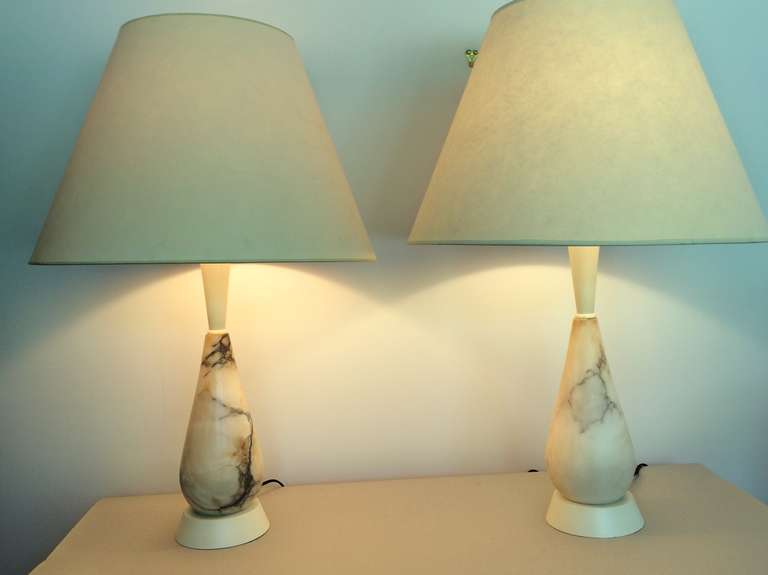 A matched pair of table lamps with white marble bodies and wooden stems, set on metal bases. The marble softly veined with black and brown coloring. Restored and renovated with cream colored gloss surface to wood and metal. Marble is signed 