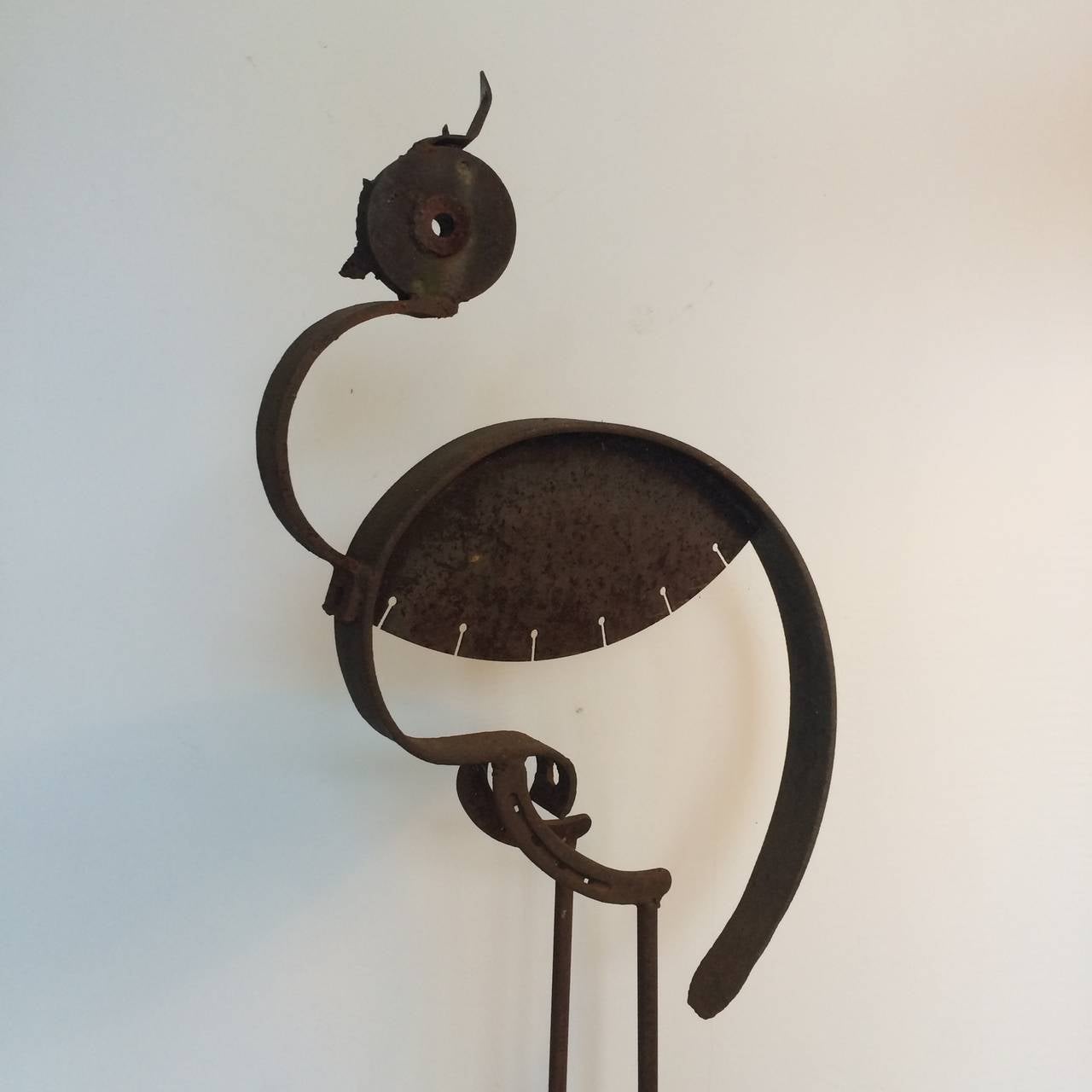 A full-scale iron sculpture of a Heron. Created from assembled iron parts. Saw blades, horseshoes and can opener fuse together to create a dynamic and whimsical sculpture. Signed on the base 