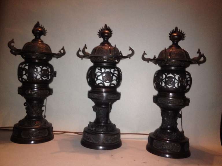 A set of three table top lanterns. beautifully cast in bronze. Crisp castings, with a variety of animal motifs. Dolphins, dragons and butterflies.
Wired for electric use, with standard Edison mounts, and original pull chain on/off switch. Newly