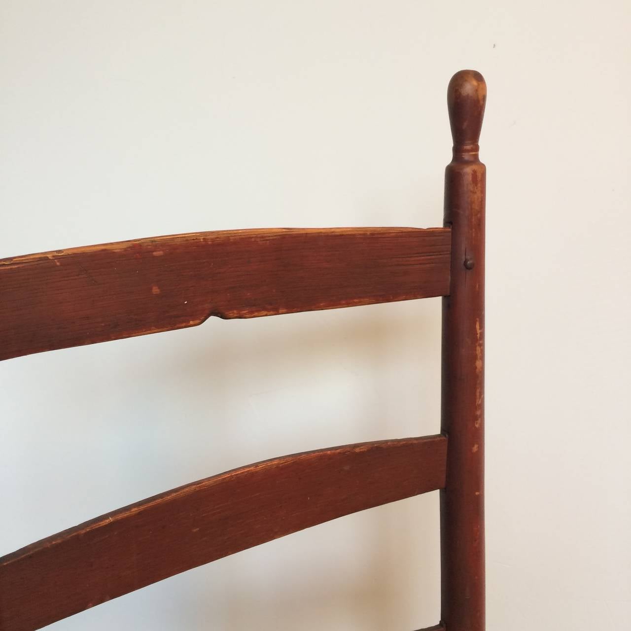 A single ladder back side chair by The United Society of Believers {The Shakers}. Retaining its original red finish and well formed rabbit ear finials. The top rail worn with a central divet from many years of being hung on a wall peg at the end of