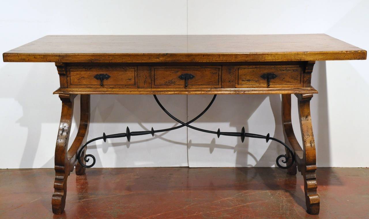 Turn of the century walnut Spanish desk on a carved base with iron crossings and flanked with three drawers across the apron, (circa 1920).
Beautiful patina and hardware.