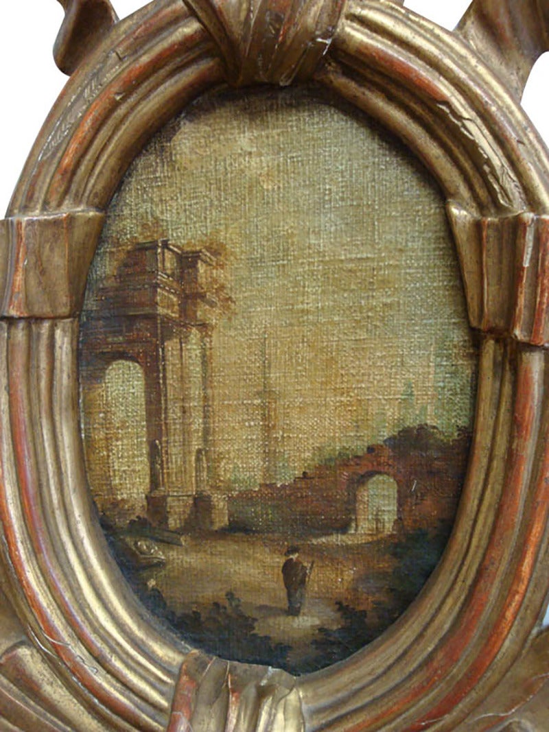 This large wall hanging clock was carved in Paris, France, circa 1780. The antique clock is topped with a cartouche frame. Inside the frame, is a small, delicate painting decorated with a traditional Louis XVI ribbon bow. The mirror is embellished