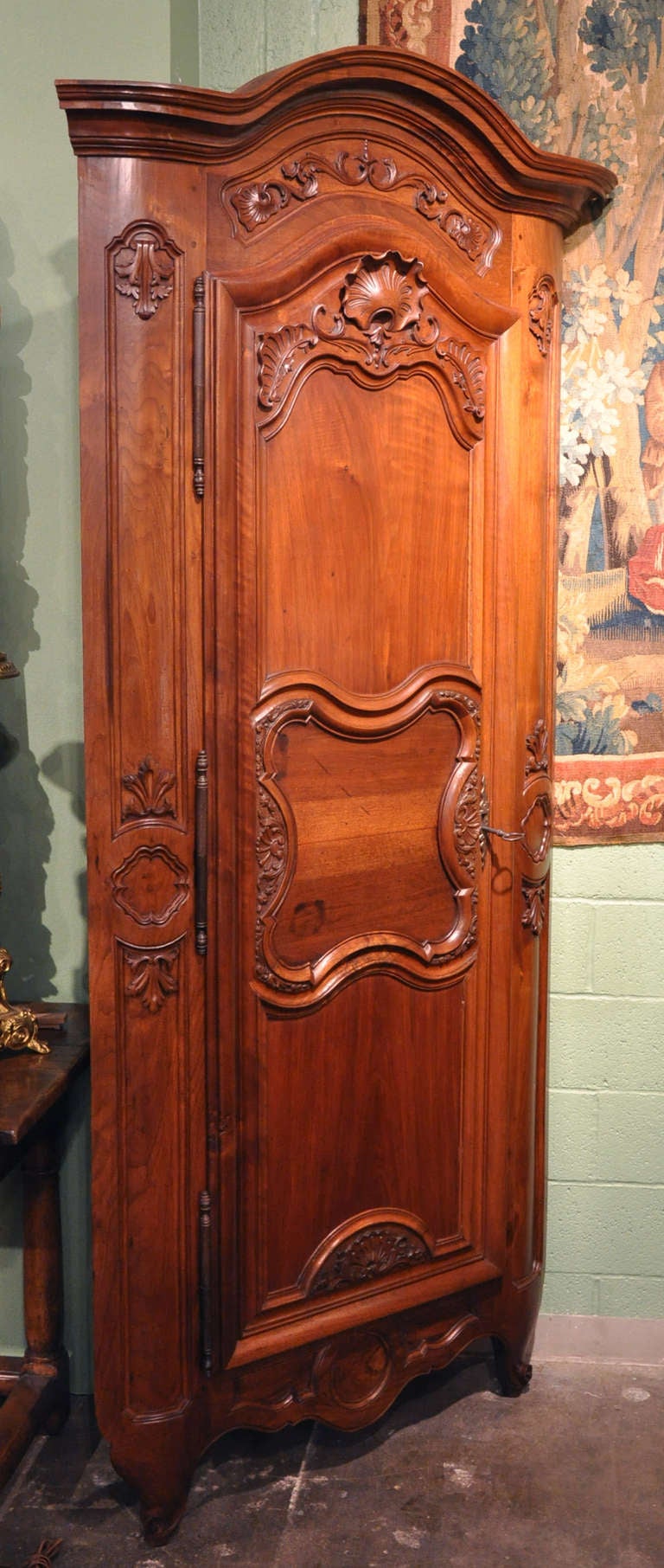 Pair of Large French Corner Cabinets from Lyon.  Composed of walnut, these exquisitely crafted, sturdy cabinets feature arched doors, beautiful carving, and stationary shelving. Original iron hinges and locks with keys.