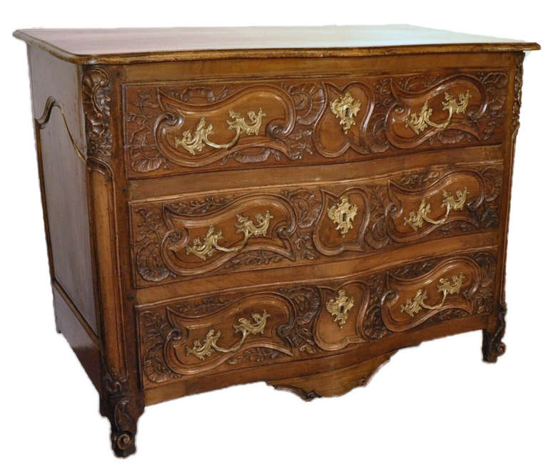 This beautifully carved, antique walnut chest of drawers was crafted in France, circa 1760. The commode features three serpentine drawers across the front with bronze hardware and a secret drawer at the bottom. The "commode lyonnaise" has