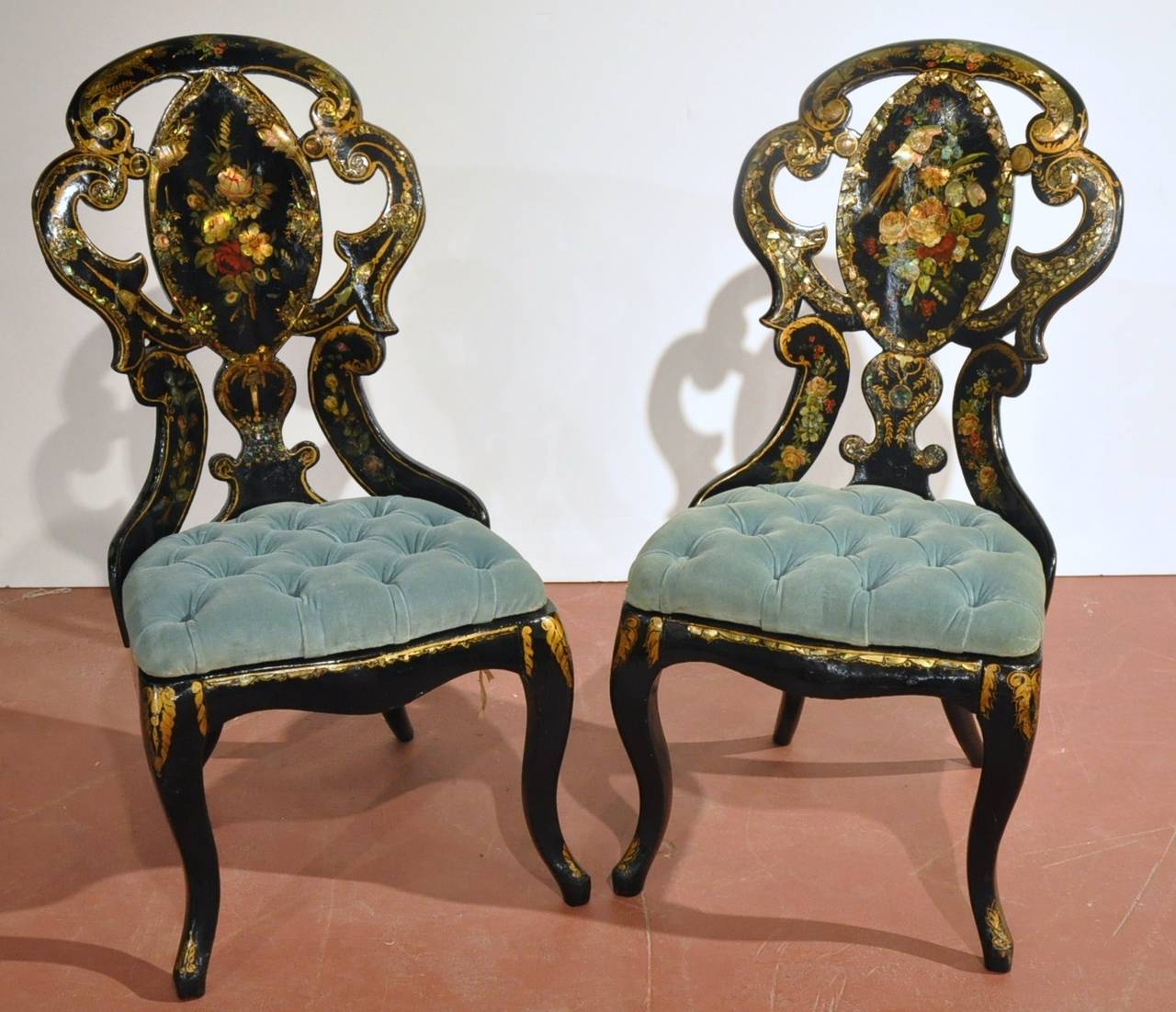 This fine, hand painted set of chairs and matching table was created in France, circa 1870. The antique set has a shiny, black lacquer frame and is embellished with mother of pearl inlays, floral designs and luxurious gold trim. The makeup, vanity