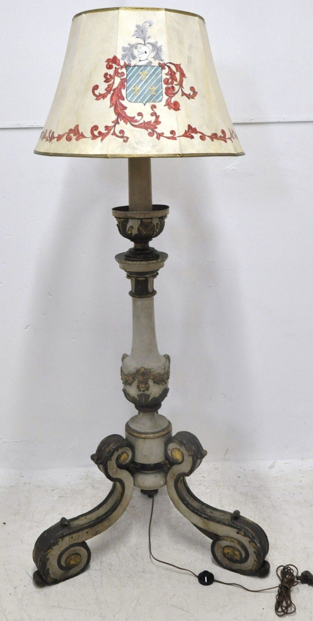 This tall antique wood floor lamp was carved in Italy, circa 1850. The light stands a wide three-leg pedestal base with intricate scroll decor and the stem is decorated with elegant carvings, embellished at the shoulder by a metal cup under the