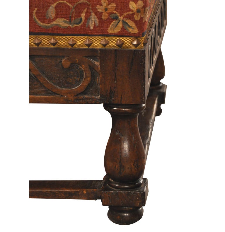 Beautifully carved walnut coffee table or ottoman from France, upholstered with 19th century Aubusson tapestry. In the manner of Cluny, the antique medieval tapestry features three women in long dresses carrying flowers and a treasure safe, flanked