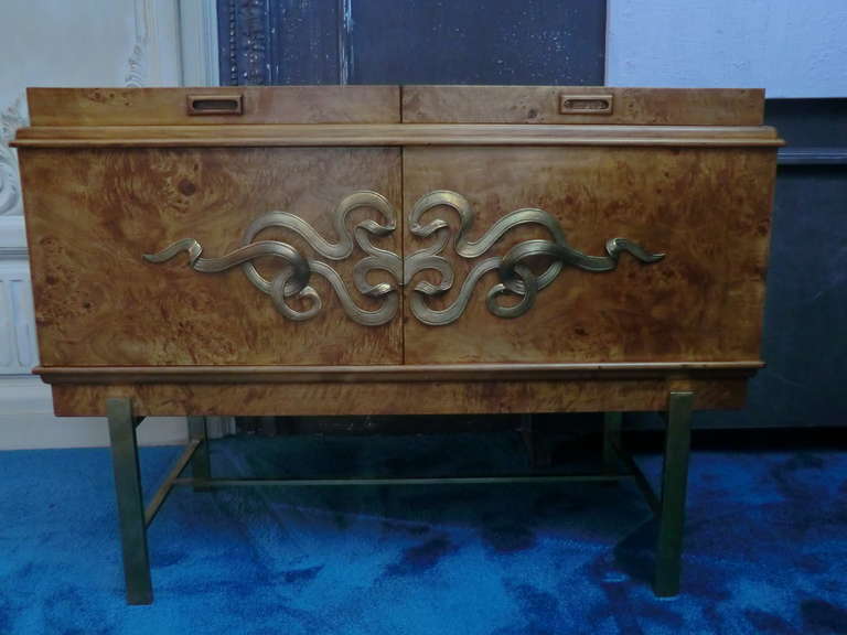 Bar cabinet in solid burlwood with natural brass decor and base, the cabinet opens on one bottom side with drawers, and on the other side on top for bottles and glasses