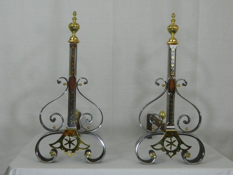 Pair of 19th century iron inlaid copper and brass chenets or andirons with a decorative finial and scrolls motif.