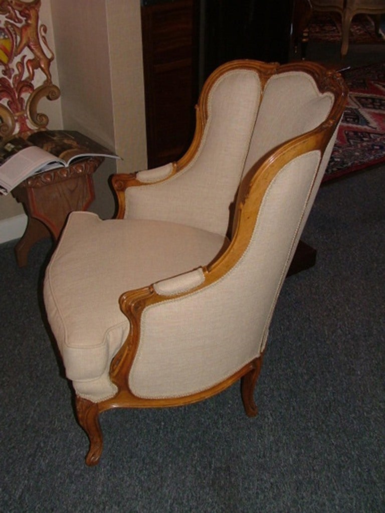 Early 20th century pair of French carved bergère chairs upholstered in cotton with down cushions.