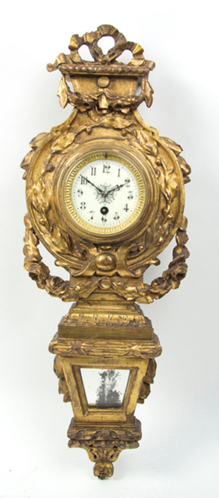 Neoclassical giltwood Cartel clock, the case carved with a ribbon-tied crest over the circular dial with Arabic numerals within a conforming bezel, having time only movement, late 19th century.