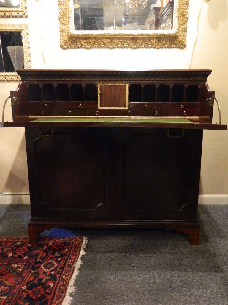 Circa 1825 English Mahogany Butler's Desk with Brass Hardware.  Drop front writing surface with interior drawers and compartments above double doors that hold two pull-out drawers
