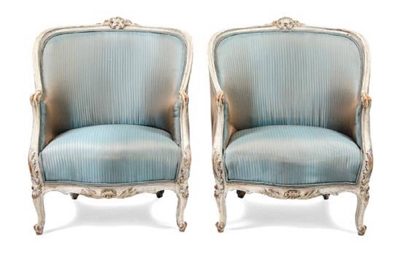 A pair of Louis XV style painted bergeres or armchairs, each with a padded back and a stuff over seat within a carved frame, raised on cabriole legs, 19th century. Dimensions: Height 33 inches.