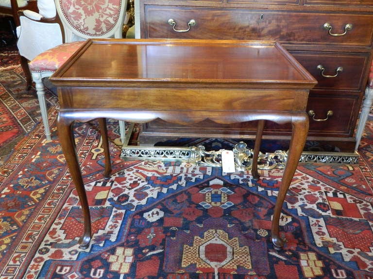 English mahogany tea table having a rectangular dished top over a plain frieze and a cyma curved apron, raised on cabriole legs terminating in pad feet, circa 1920s.